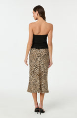 The woman is wearing a strapless black top and a high-waisted, ankle-length skirt with a leopard print pattern. She is also wearing black high-heeled shoes.