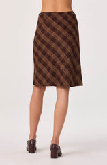 A knee-length skirt with a brown and tan plaid pattern, worn with dark brown block-heeled shoes.