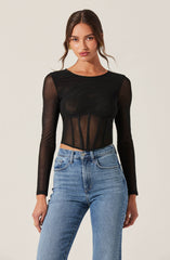 A woman is wearing a black long-sleeve top with sheer, see-through fabric and structured paneling at the waist. She is also wearing high-waisted, light-wash blue jeans.