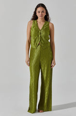 A woman is wearing a shiny, textured, sleeveless vest and matching high-waisted, wide-leg pants in a bright green color.